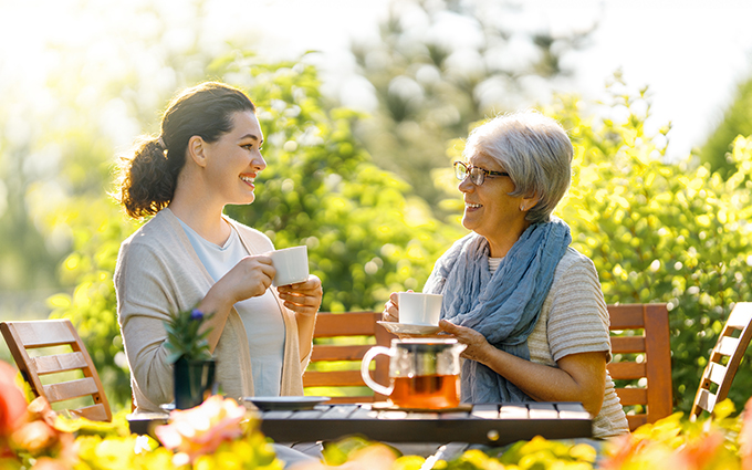 two ladies drinking tea outside in a garden