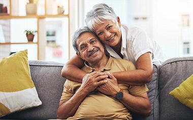 an elderly couple hugging together in a living room